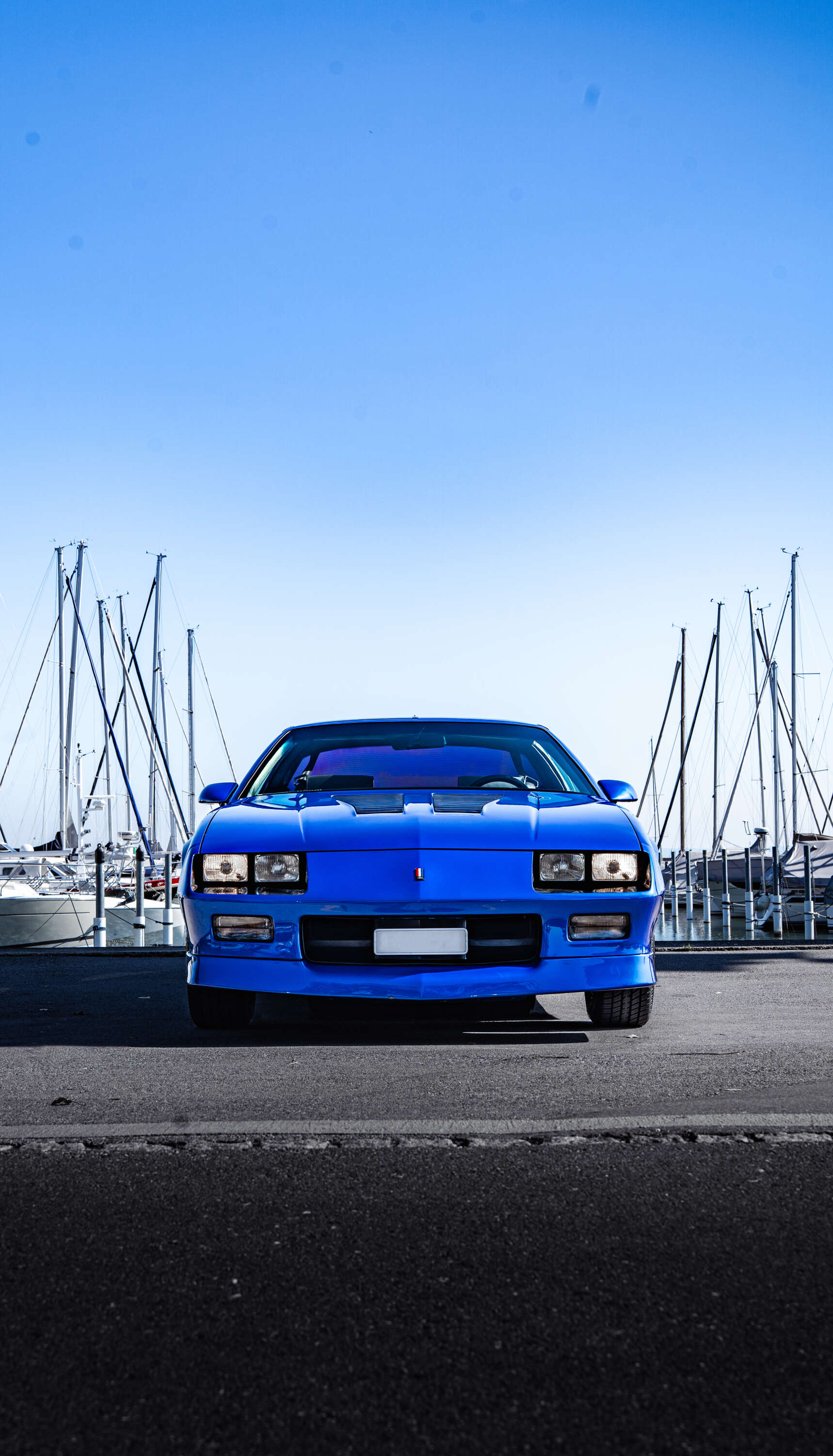 Blauer Sportwagen vor Yachthafen